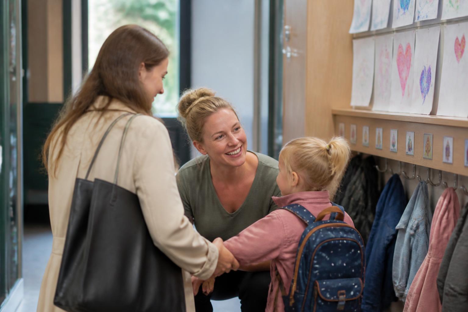 Medewerker verwelkomt een ouder en kind bij de deur in de hal